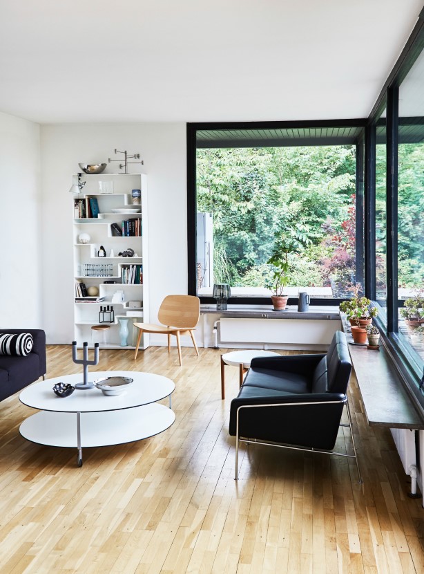 Den fredede nordsjællandske natur vælter ind i stuen gennem husets store vinduer. Sofaen i læder er Arne Jacobsens lufthavssofa, som Stine fandt i storskrald for mange år siden og siden har fået ombetrukket. På det runde sofabord fra Zanotta står en moderne udgave af kammerstagen fra Menu.