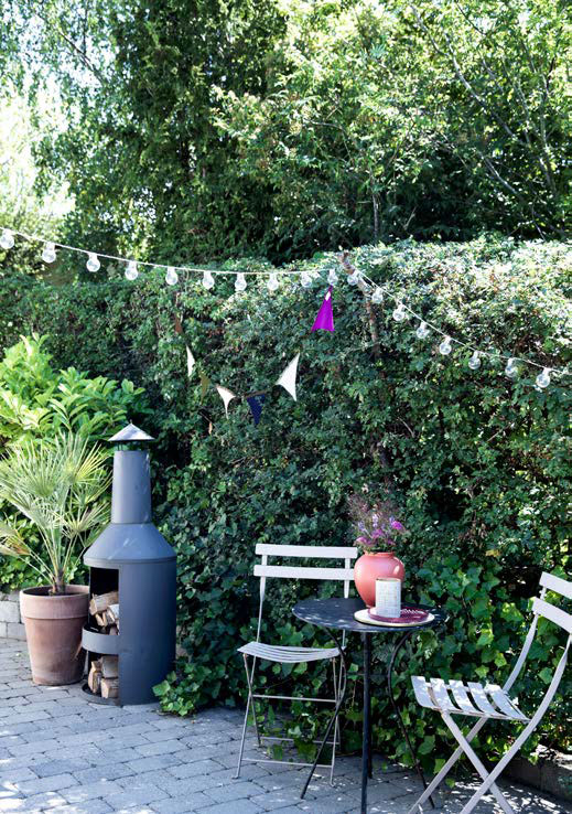 Louise har indrettet flere små kroge på terrassen, der går hele vejen rundt om huset. Cafébordet har hun fundet i storskrald og spraymalet sort. Ovnen er købt i Silvan.