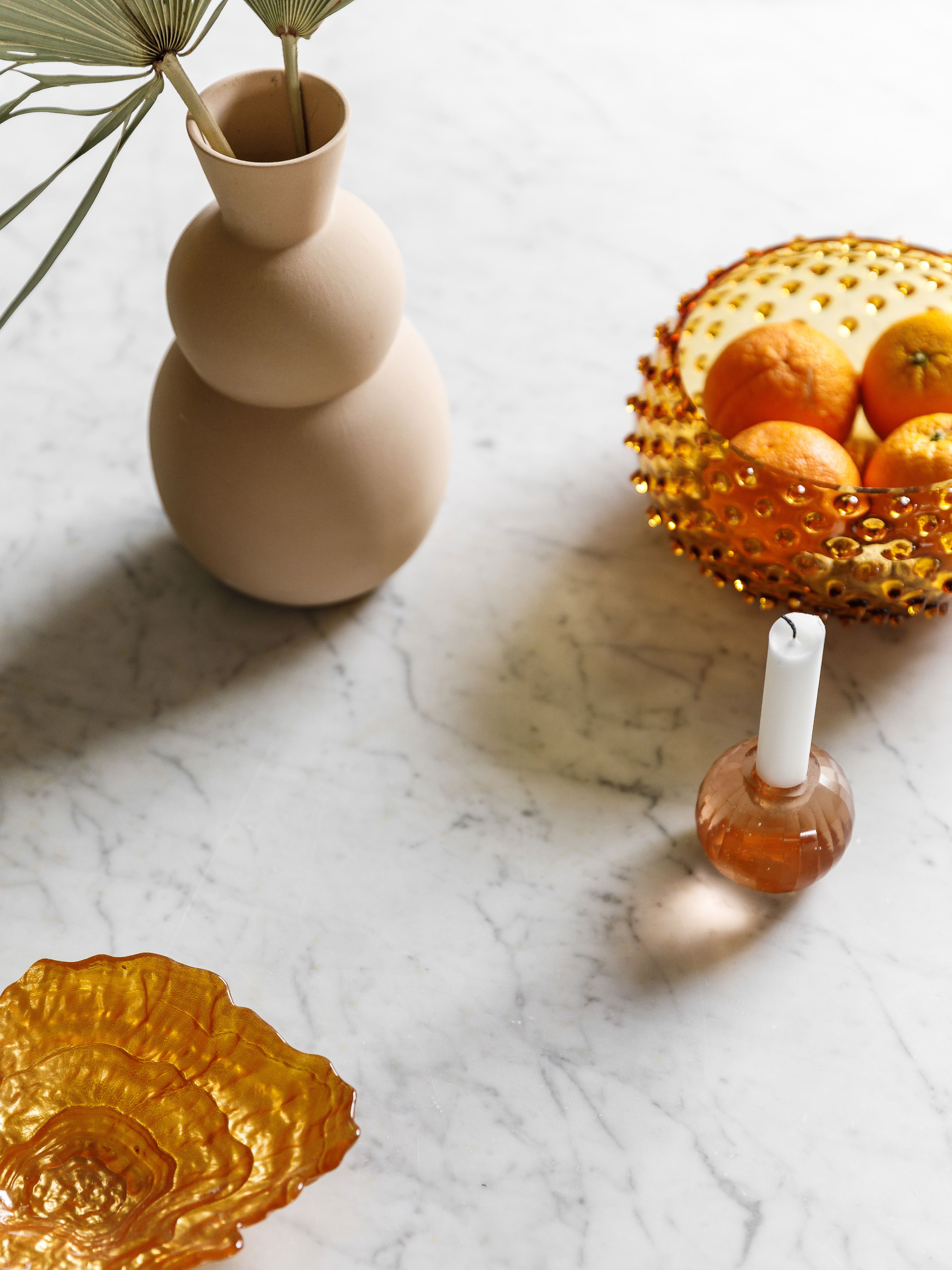 De varme detaljer kommer i fokus med det kølige marmorbord som underlag. Vasen er fra H&M Home, frugtfadet er fra Anna Von Lipa, købt hos Fabrek, stagen er fra Tine K Home og muslingefadet er fra Hay.