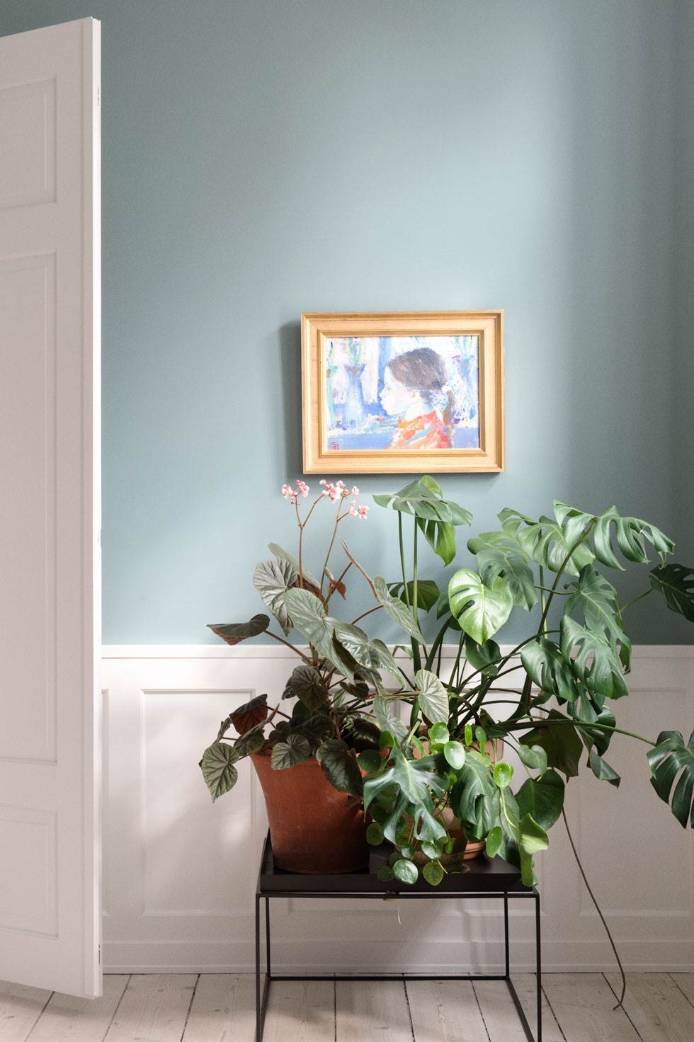 På sofabordet fra Hay har Trine samlet sine grønne planter. Billedet på væggen er af Poul S. Nielsen, der blev kaldt den blå maler, og som har boet i lejligheden, hvor han også har malet dette portræt af naboens datter. Trine fandt værket på Lauritz.com. Kunstneren var meget glad for blå, og alt i lejligheden var malet blåt, da Trine overtog lejligheden, så derfor var det svært at komme udenom farven blå i istandsættelsen. Foto: Gyrithe Lemche