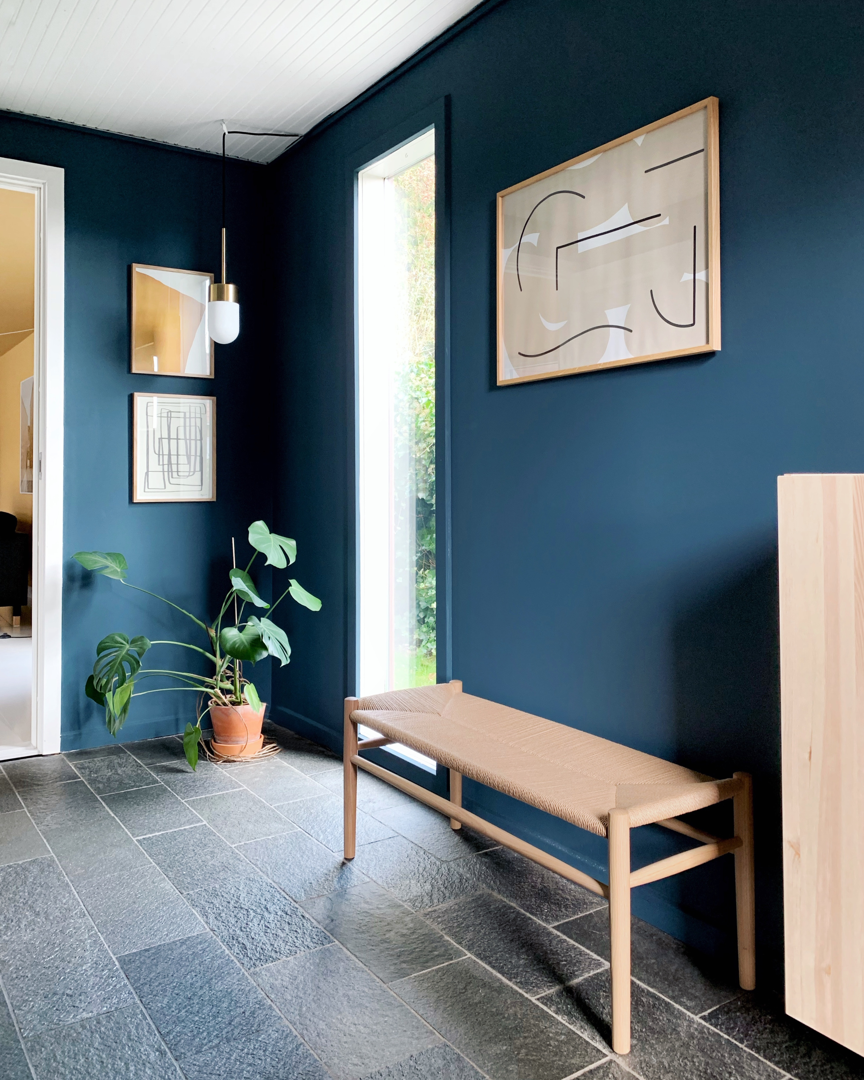 Den ikoniske bænk, J83B, er designet af møbelarkitekt Jørgen Bækmark for FDB Møbler. Lampen Vox Pendant er fra RUBN Lighting. Væggen i entreen er malet med Industrial Blue fra Jotun Lady.