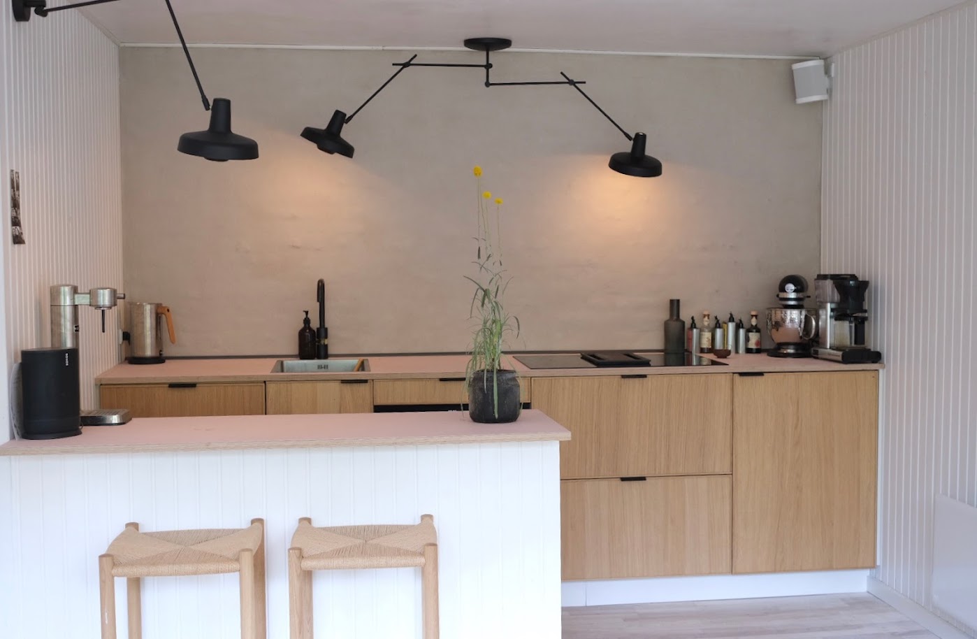 Den tidligere hvide murstensvæg er blevet overtrukket med Conteco for at bibeholde det rå look. Køkkenet er fra IKEA og med en lyserød linoleum bordplade