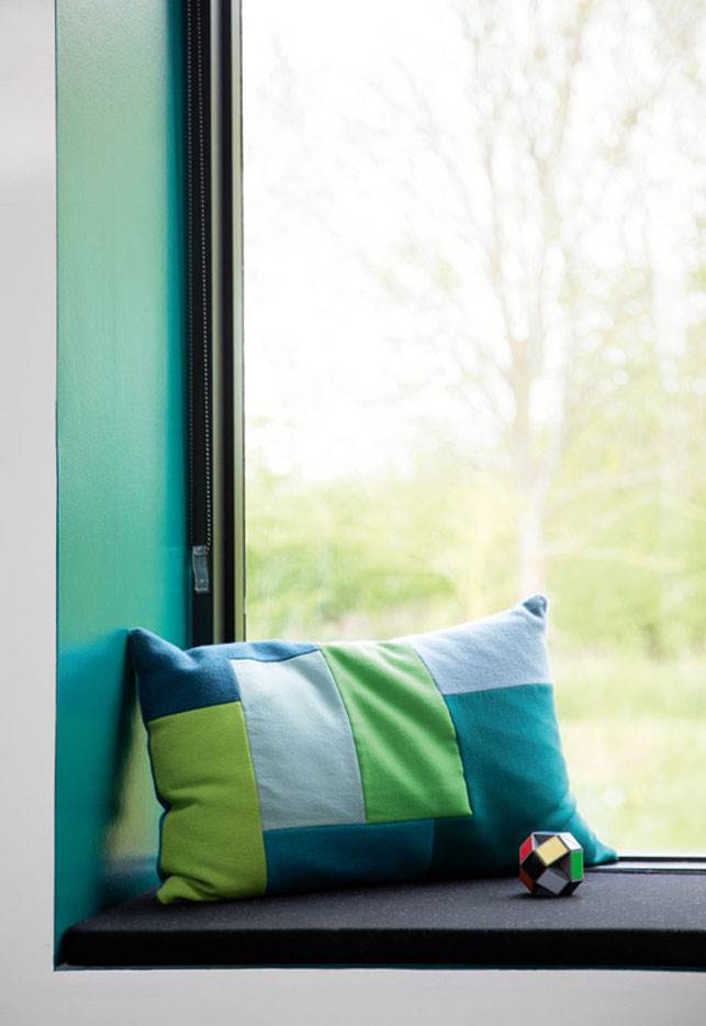 Den grønmalede vinduesniche indbyder til, at man tager en pause for at sidde og kigge ud på naturen. Normann Copenhagen har lignende puder.